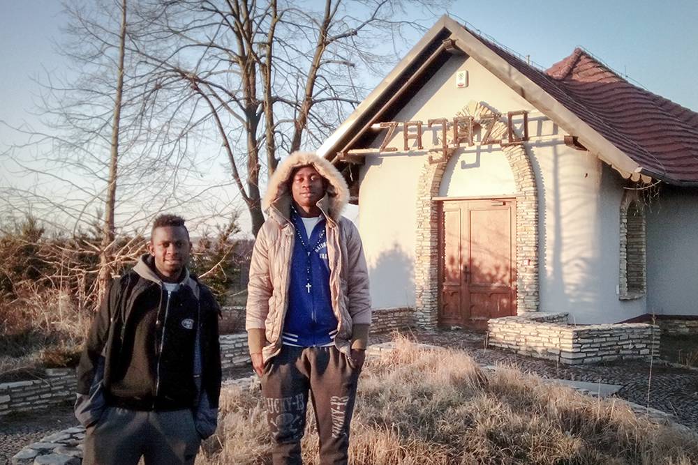 Two Cameroonian football players – Austin and Nelson – stand in front of their “home” in a village in the south of Poland, which they shared with fellow footballers – two Cameroonians and three Brazilians - throughout the 2014/2015 season. The building, located at the roadside, is a tavern that went bankrupt and was turned into a dwelling. Southern Poland, Winter 2015. (Photo Paweł Banaś)