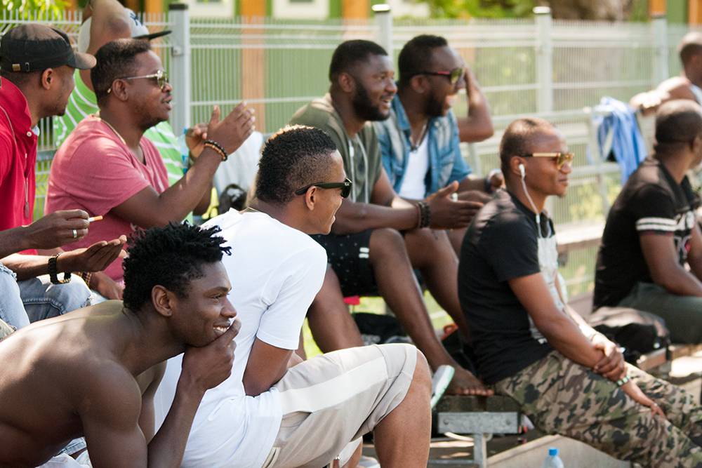 The crowd gathered during a football game in the park. West African migrants often come to watch games and trainings, but also to socialize and carry out business activities. Many sitting in the bleachers are former football players who still reside in Poland. Warsaw, Summer 2016. (Photo Paweł Banaś)
