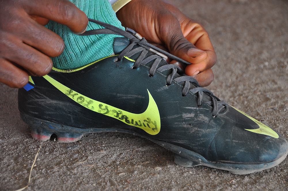 Uros Kovac - football, boot, Buea, 2014. An inscription on a footballer’s boot reads “Holy Trinity”. Charismatic Christianity allows the young athletes the grapple with uncertainty. Buea, Cameroon, December 2014. Photo by Uroš Kovač.